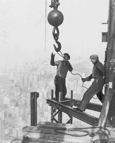 1931 photo Two iron workers straddle steel girders on top of the 